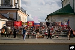 Orang-orang berdiri di dekat tugu peringatan dadakan untuk mengenang Yevgeny Prigozhin dan anggota wagner lain yang tewas dalam kecelakaan pesawat bersamanya tahun lalu, di dekat Kremlin, di Moskow, Rusia, 29 Juli 2024. (Pavel Bednyakov/AP)