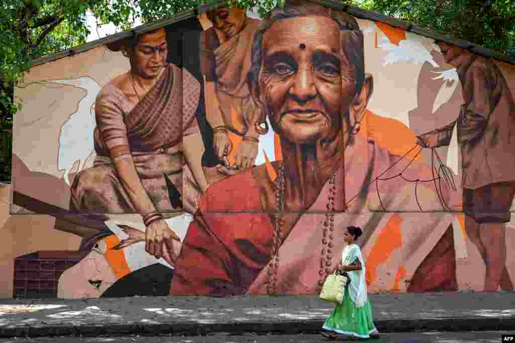 A woman walks past a mural of depicting fisherwomen, in Mumbai, India.