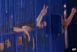 FILE - Detainees flash gestures at a Bangkok immigration detention center in Bangkok, Thailand, Jan. 21, 2019. According to the son of one former detainee, more than 50 adult Uyghur men remain in Thailand's immigration detention facilities.