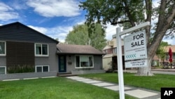 FILE - A for sale sign stands outside a single-family home in Englewood, Colorado, June 27, 2024. 