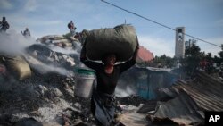 A seller saves items from the burned ruins of the Shada Market in the Petion-ville area of Port-au-Prince, Haiti.