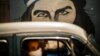 ARCHIVO - En plena pandemia del Covid, doersonas con mascarillas pasan a bordo de un auto frente a un mural de Ernesto "Che" Guevara en La Habana, en abril de 2020.