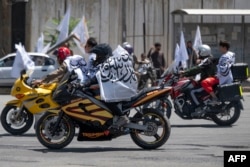 Pendukung Taliban mengendarai sepeda motor dengan bendera Taliban selama perayaan ulang tahun kedua pengambilalihan negara di alun-alun Ahmad Shah Massoud di Kabul pada 15 Agustus 2023. (Foto: AFP)