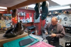 Seorang karyawan sedang memperbaiki sepasang sepatu di Alpha Shoe Repair Corp. di New York, Jumat, 3 Februari 2023. (AP/Mary Altaffer)
