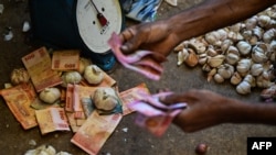 ILUSTRASI - Seorang vendor memegang uang kertas Sri Lanka saat bekerja di sebuah pasar di Kolombo, 13 Desember 2023. (Ishara S.KODIKARA/AFP). IMF mencapai kesepakatan tingkat staf dengan Sri Lanka, untuk membuka jalan bagi pencairan dana 337 juta dolar AS. 