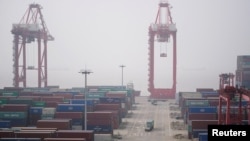 FILE - Trucks move past containers at the Yangshan Deep Water Port in Shanghai, China, Jan. 13, 2022.