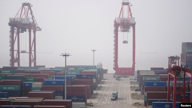 FILE - Trucks move past containers at the Yangshan Deep Water Port in Shanghai, China, Jan. 13, 2022.