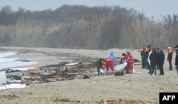 This photo obtained from Italian news agency Ansa, taken on Feb 26, 2023 shows rescuers handling a body bag at the site of a shipwreck in Steccato di Cutro.