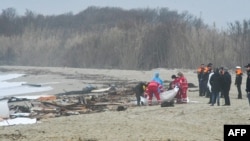 This photo obtained from Italian news agency Ansa, taken on Feb 26, 2023 shows rescuers handling a body bag at the site of a shipwreck in Steccato di Cutro.
