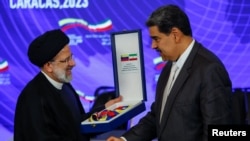 Venezuela's President Nicolas Maduro presents Iranian President Ebrahim Raisi with the "Orden Libertadores y Libertadoras de Venezuela" decoration as they meet at the Miraflores Palace, in Caracas, Venezuela, June 12, 2023. 