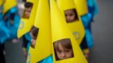 Children wearing hoods as penitents take part in a procession during the eve of Holy Week at Salesians school in Cordoba, southern Spain.