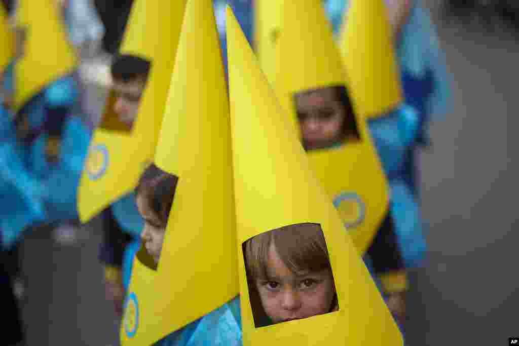 Children wearing hoods as penitents take part in a procession during the eve of Holy Week at Salesians school in Cordoba, southern Spain.
