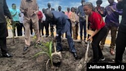 FILE - Rita Joy Samantha Burk (R), assisted by Africano Mande (L) plants a tree on the premises of the South Sudan National Revenue Authority in Juba. VOA/Juliana Siapai