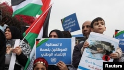 Para demonstran membawa plakat dan bendera Palestina dalam aksi protes di luar kantor UNRWA di Beirut pada 27 Maret 2024, untuk mendukung salah satu staf UNRWA yang diskors. (Foto: Reuters/Mohamed Azakir) 