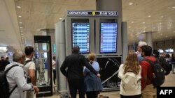 2023年10月7日，以色列特拉维夫附近的本古里安国际机场，乘客们看着出发牌，航班因哈马斯袭击而取消。