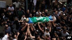 Palestinians carry the body of militant Hamza Kharyoush wrapped in a Hamas flag in the Nur Shams refugee camp near the city of Tulkarem, in the occupied West Bank, May 6, 2023.