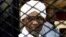 FILE - Sudan's former president Omar Hassan al-Bashir smiles as he is seen inside a cage at the courthouse where he is facing corruption charges, in Khartoum, Sudan August 31, 2019.
