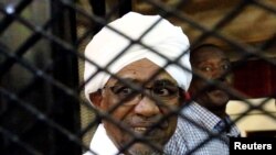 FILE - Sudan's former president Omar Hassan al-Bashir smiles as he is seen inside a cage at the courthouse where he is facing corruption charges, in Khartoum, Sudan August 31, 2019.