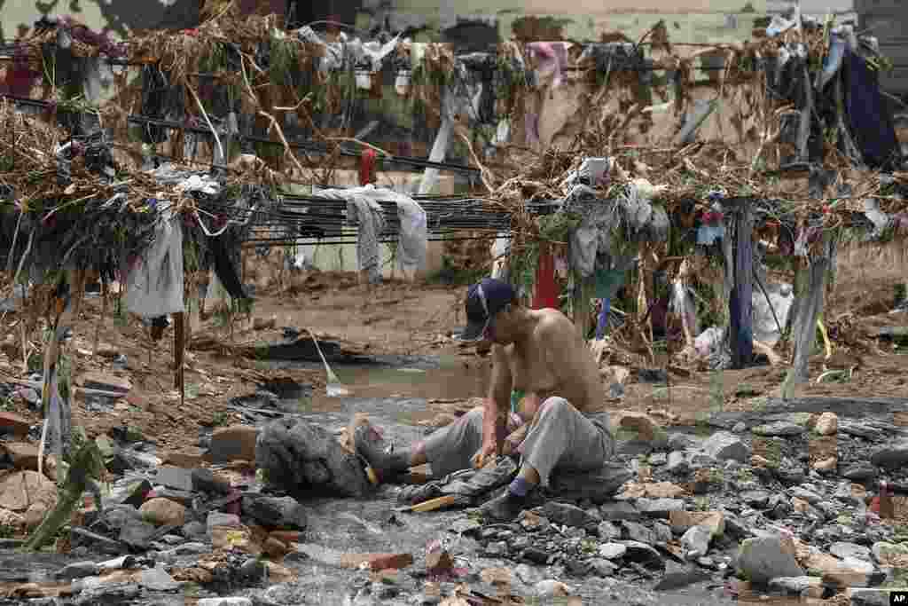 A man washes his clothes in a stream near debris left over after flood waters devastated the village of Nanxinfang on the outskirts of Beijing.