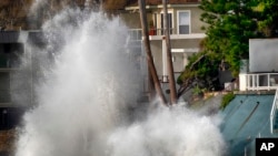 Waves smash against a sea wall next to homes along the California coast in Malibu Beach, Calif., on Dec. 29, 2023.