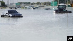 Vehicles sit abandoned in floodwater covering a major road in Dubai, United Arab Emirates, Wednesday, April 17, 2024. (AP Photo/Jon Gambrell)