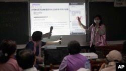 Volunteers of Fake News Cleaner guide students through the LINE app to identify fake news during a class in Kaohsiung City, southern Taiwan, Thursday, March 16, 2023. (AP Photo/Chiang Ying-ying)