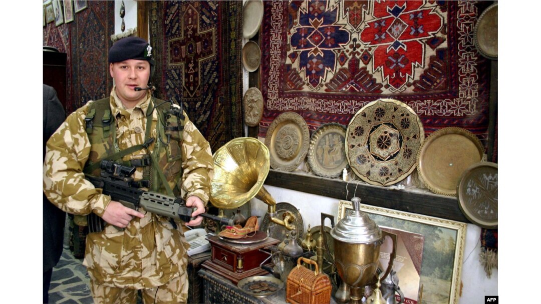 ILUSTRASI - Seorang tentara Inggris berpose di sebuah toko yang memajang karpet tua dan barang antik saat berpatroli di distrik kota lama Basra, Irak, 23 Februari 2004. (AFP /Hani AL-OBEIDI)