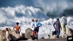 Beachgoers watch as turbulent surf pounds the coast at Manhattan Beach in California, Dec. 28, 2023.