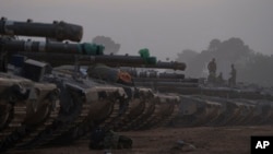 Israeli soldiers stand on top of a tank in a staging area at the Israeli-Gaza border in southern Israel, Jan. 1, 2024.
