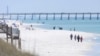 FILE - People walk along the shoreline in Navarre Beach, Fla., on March 27, 2013.