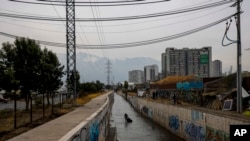 FILE - A homeless Chilean man collects items from the El Zanjón de la Aguada water canal in hopes of reselling them in Santiago, Chile, May 15, 2024. 