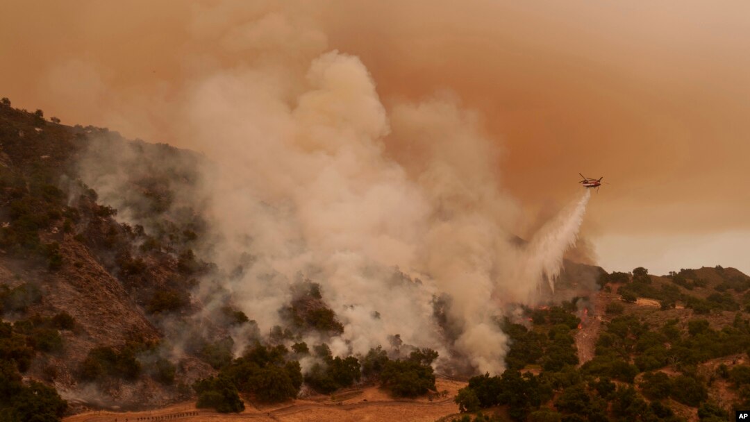A water-dropping helicopter drops on flames from the advancing Lake Fire in Los Olivos, Calif., July 6, 2024. 