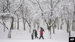 People walk through the snow in Goyang, South Korea, Saturday, Dec. 30, 2023. South Korean Meteorological Administration issued a heavy snow advisory for some parts of the Korea peninsula. 