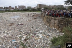 FILE - People watch from the edge of a quarry where human remains were found in Mukuru Kwa Njenga area, in Nairobi, Kenya, July 13, 2024.