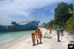 In this handout photo provided by the Philippine Coast Guard (PCG), PCG personnel walk beside the MV Lady Mary Joy 3 that caught fire in Basilan, southern Philippines, March 30, 2023.