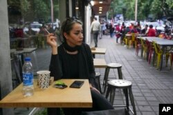 A woman sits in the alfresco dining area of a cafe at Tajrish commercial district without wearing her mandatory Islamic headscarf in northern Tehran, Iran, April 29, 2023.