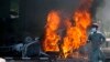 FILE - A man runs past a burning car set on fire by angry supporters of Pakistan's former Prime Minister Imran Khan during a protest against the arrest of their leader, in Peshawar, Pakistan, May 10, 2023.