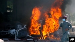 FILE - A man runs past a burning car set on fire by angry supporters of Pakistan's former Prime Minister Imran Khan during a protest against the arrest of their leader, in Peshawar, Pakistan, May 10, 2023.