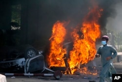 FILE - A man runs past a burning car set on fire by angry supporters of Pakistan's former Prime Minister Imran Khan during a protest against the arrest of their leader, in Peshawar, Pakistan, May 10, 2023.