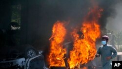 Seorang pria berlari melewati mobil yang terbakar dalam aksi protes menentang penangkapan terhadap mantan Perdana Menteri Pakistan Imran Khan, di Peshawar, Pakistan, pada 10 Mei 2023. (Foto: AP/Muhammad Sajjad)