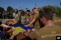 Ukrajinski vojnici iz 3. jurišne brigade pozdravljaju poslednji put svog poginulog druga Vadima "Gagarina" Belova, tokom sahrane na groblju u Polonu, oblast Hmeljnicki, u Ukrajini, 13. septembra 2023. Vadin je ubijen tokom jurišne misije kod Bahmuta.