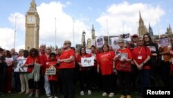 FILE - People gather in Westminster on May 19, 2024, to remember those who lost their lives in the U.K.'s decades-long infected blood scandal. Britain's government said Tuesday the victims of the scandal will start receiving final compensation payments this year.  