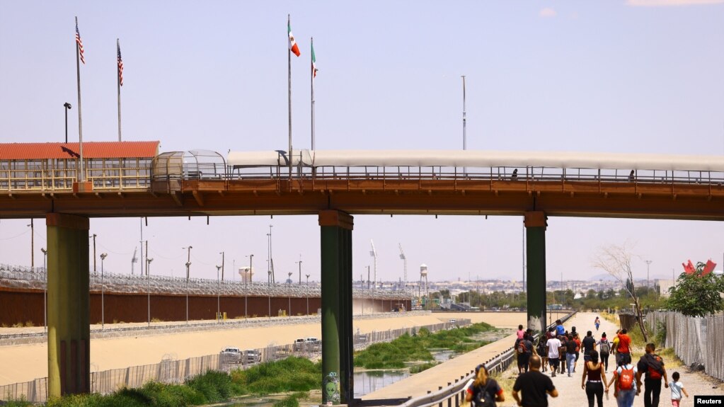 Migrantes caminan cerca del Puente Internacional Paso del Norte en Ciudad Juárez, México, el 26 de julio de 2023.