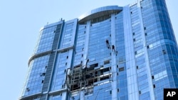 This photo released by the governor of the Saratov region, Roman Busargin, in his official Telegram channel on Aug. 26, 2024, shows municipal employees working at the side of a damaged building after a drone attack on the city of Saratov, Russia.