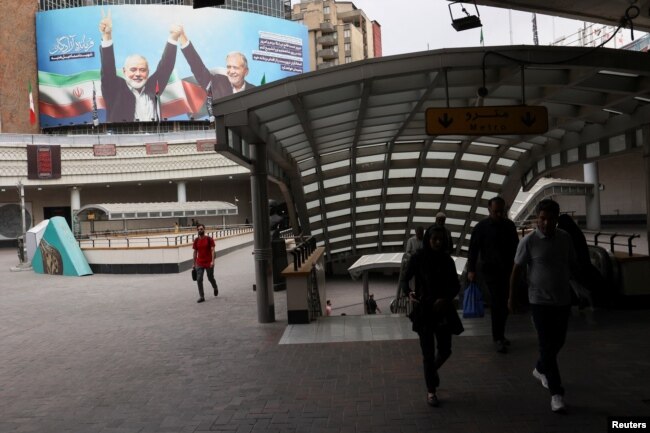 Papan iklan bergambar mendiang pemimpin Hamas Ismail Haniyeh dan Presiden Iran, Masoud Pezeshkian, dipajang di sebuah gedung di jalan di Teheran, Iran, 12 Agustus 2024. (Majid Asgaripour/WANA (West Asia News Agency) via REUTERS)