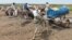 Men queue to fill tanks with water from a well in Gadaref, Sudan, on Aug. 17, 2023. For more than three months, millions have been rationing water and electricity, unable to reach the few health care facilities that still function in the country.