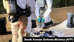 This handout photo released on June 2, 2024 shows South Korean military officers check unidentified objects believed to be North Korean trash from balloons that crossed the inter-Korea border, on a street in Seoul.