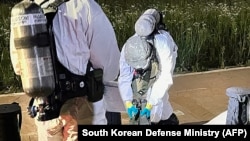 Dua tentara Korea Selatan memeriksa benda tak dikenal yang diyakini sebagai sampah Korea Utara dari balon yang melintasi perbatasan antar-Korea, di sebuah jalan di Seoul, pada dini hari 2 Juni 2024. (Kementerian Pertahanan Korea Selatan/AFP)