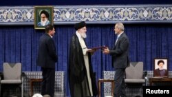 Pemimpin Tertinggi Iran Ayatollah Ali Khamenei memberikan dekrit Presiden kepada presiden baru Iran, Masoud Pezeshkian, dalam upacara pengesahan di Teheran, 28 Juli 2024. (WANA via Reuters)