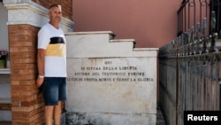 Mauro Petrarca poses for a photo next to a memorial in honor of six men, including his great grandfather, who were hanged by the German army in 1943, in Fornelli, Italy, Aug. 2, 2023. 